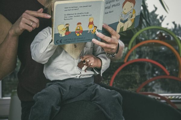 Mutter und Kind lesen das "Wenn ich mal muss" Buch. Kind trägt die Pfützenschutz Hose