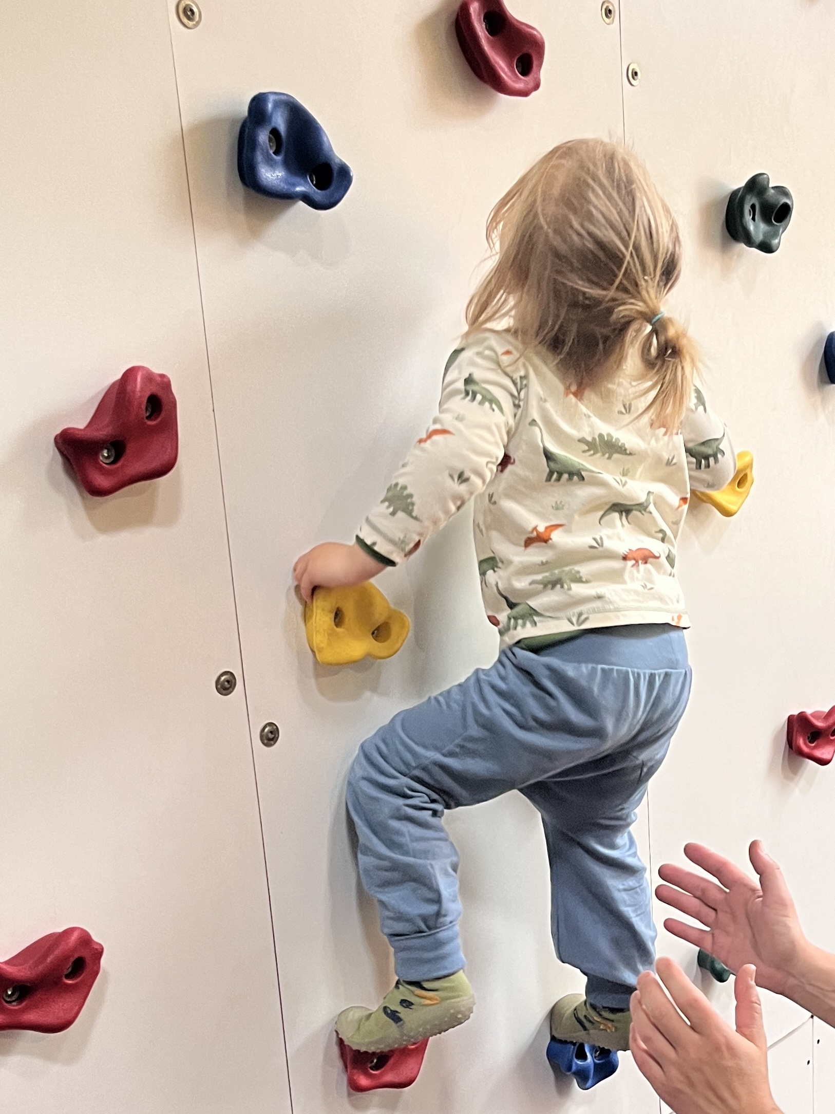 Kind klettert in Windelweg Hose Blaubär eine Kletterwand hoch