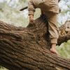 Kind klettert auf einem Baum und trägt Windelweg Hose Ufersand als Unterstützung beim Trockenwerden