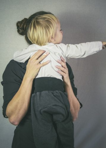 Kind auf dem Arm mit der Mama, zeigt nach rechts